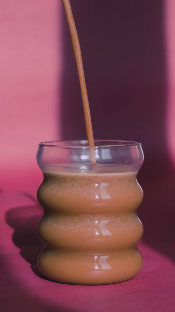 Kakaodrink wird ins Glas gegossen – das Glas füllt sich langsam.